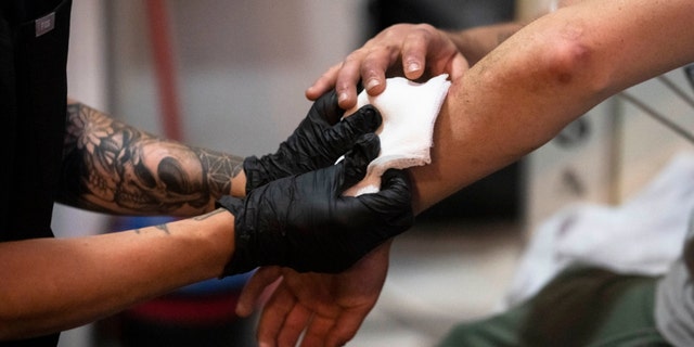 A nurse treats a man's skin wounds