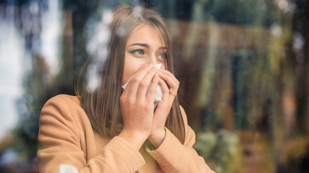 A woman blows her nose