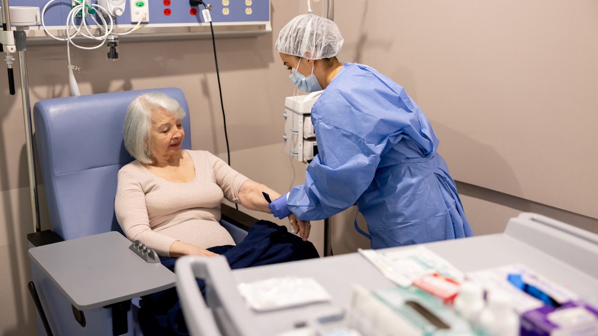 Nurse prepares a cancer patient for chemotherapy in a hospital