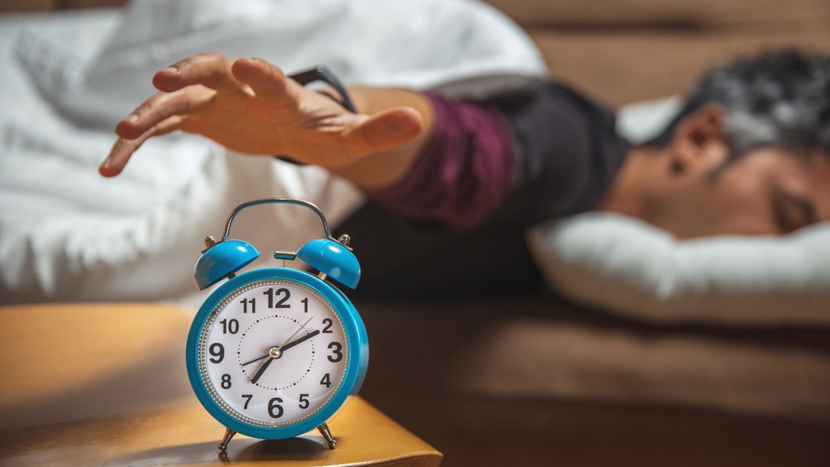 Man hitting snooze button