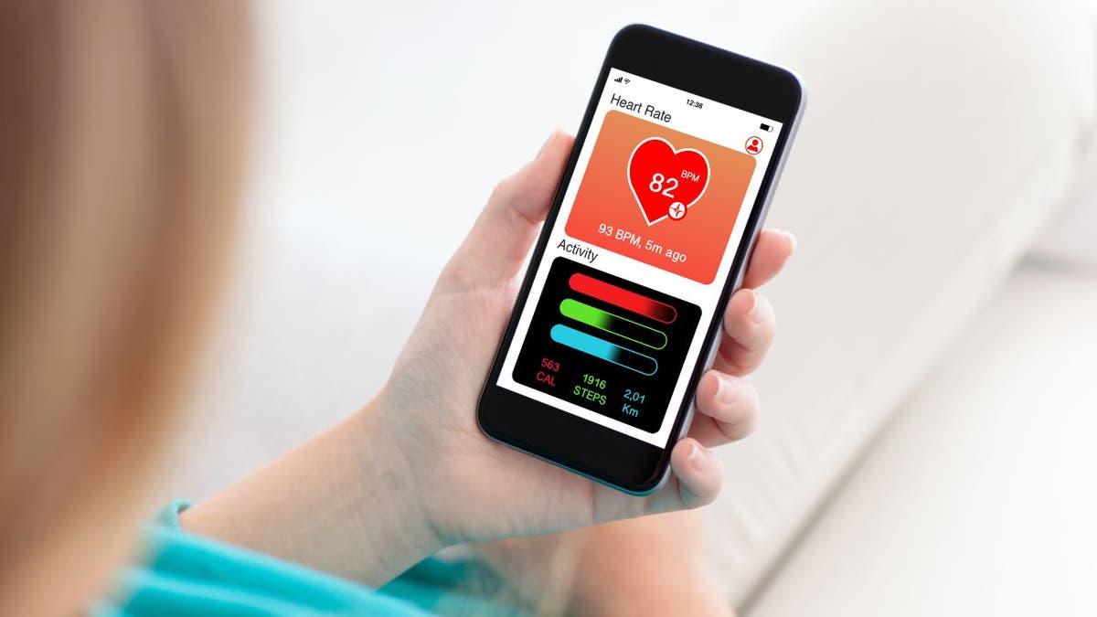 Stock photo shows woman checking health app on smartphone